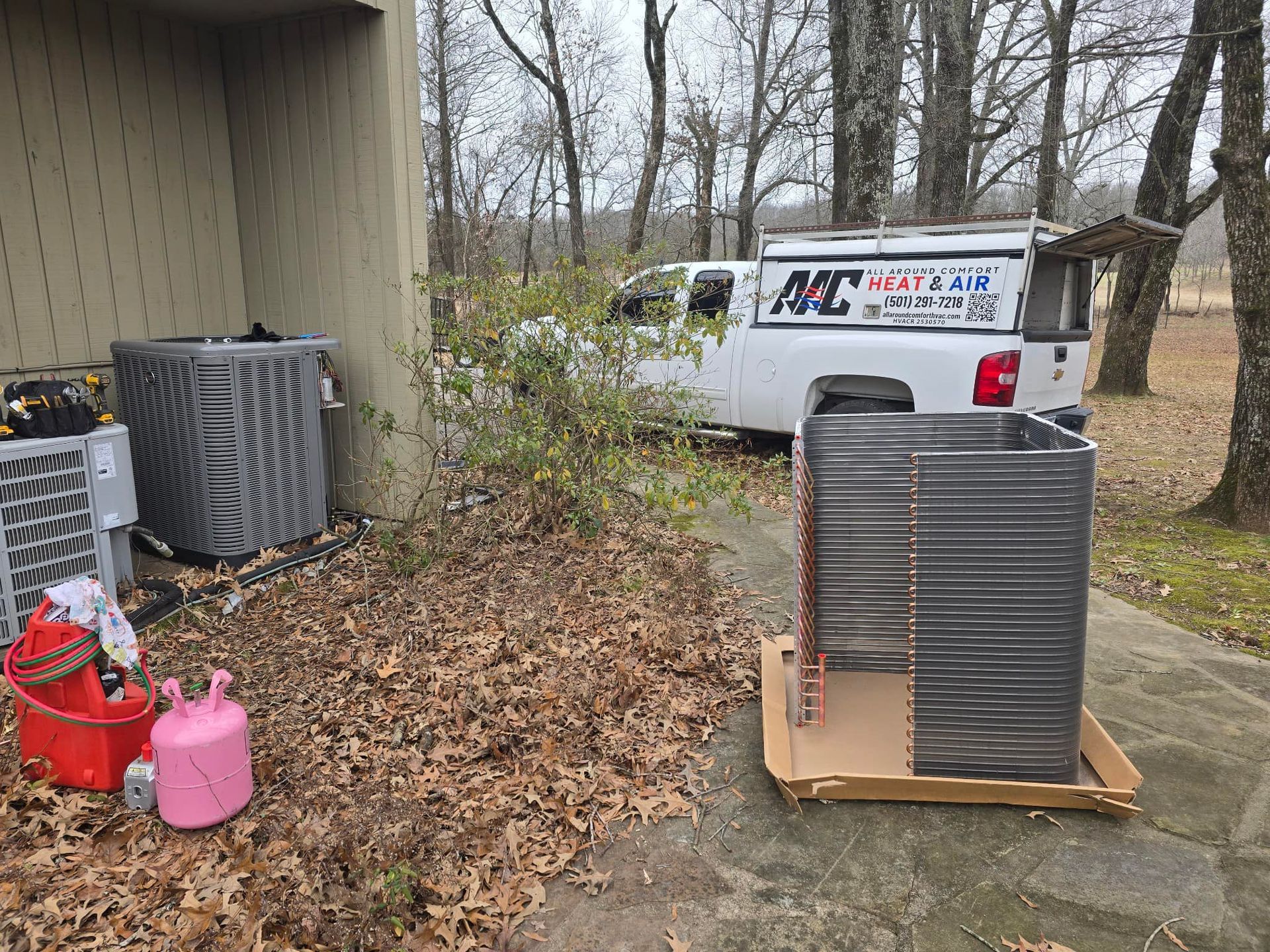 A white truck is parked next to a stack of air conditioners.