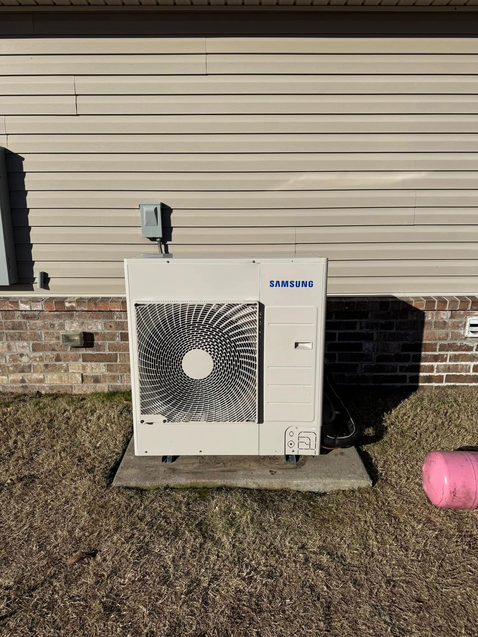 A white air conditioner is sitting on the side of a house.