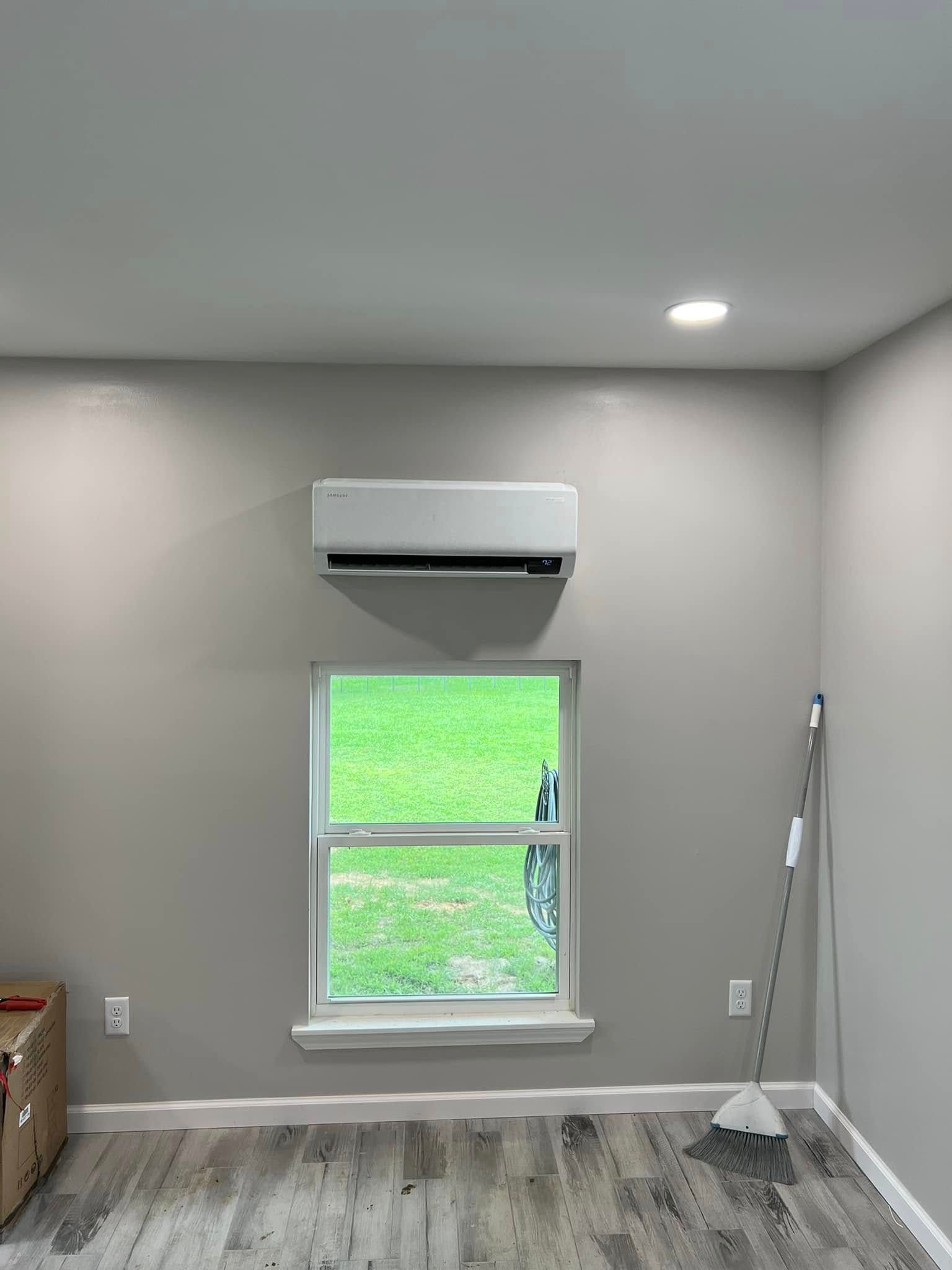 A room with a window and a fan on the wall.