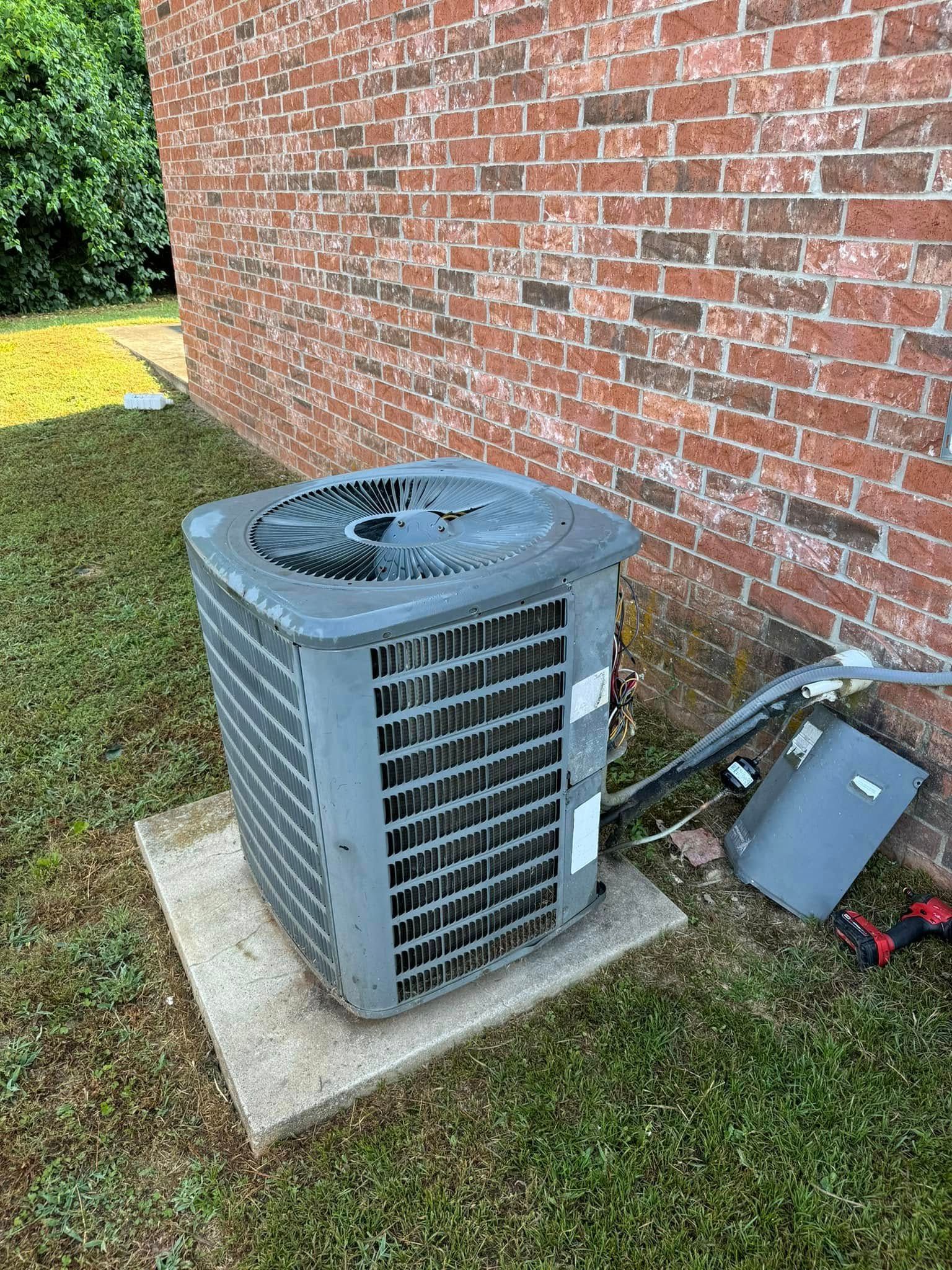 An air conditioner is sitting on the side of a brick building.