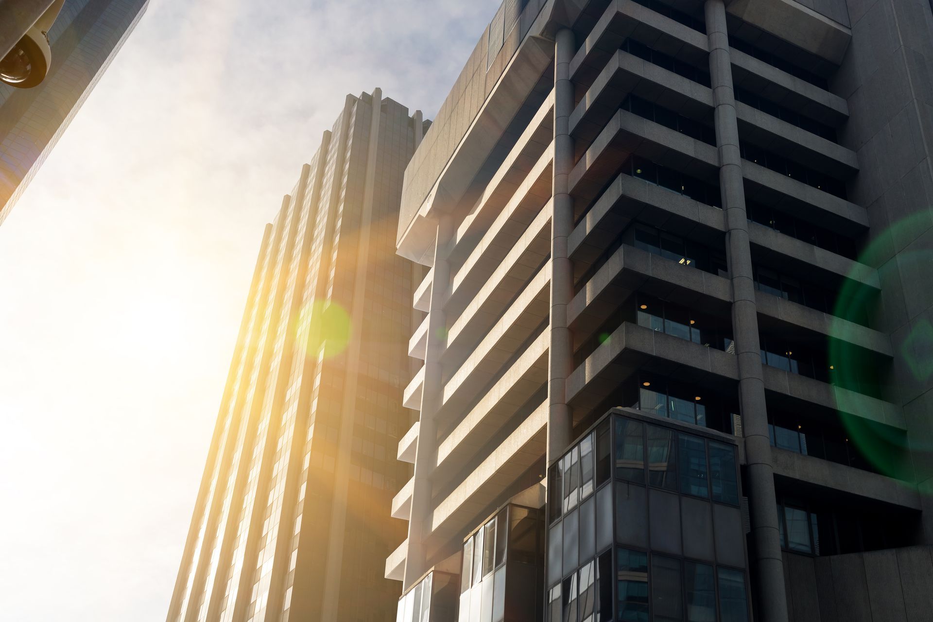 Low-angle view of modern, gray high-rise buildings bathed in sunlight.