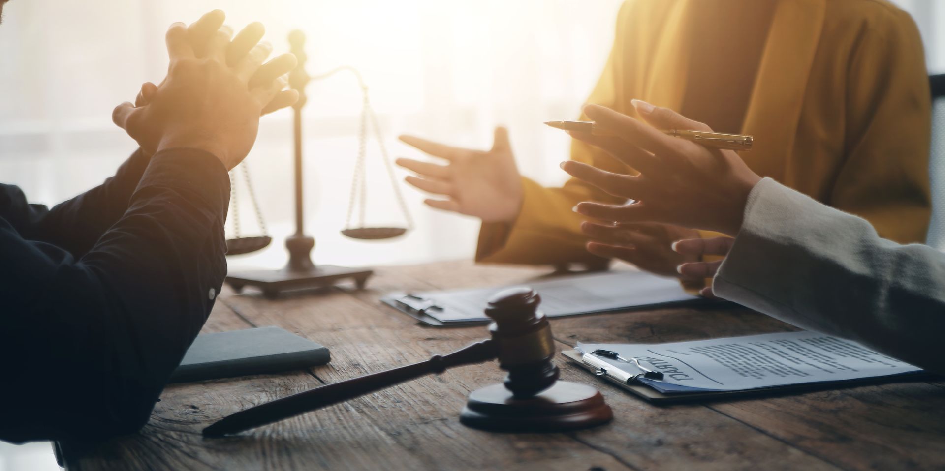 A group of people are sitting at a table with a judge 's gavel and scales of justice.