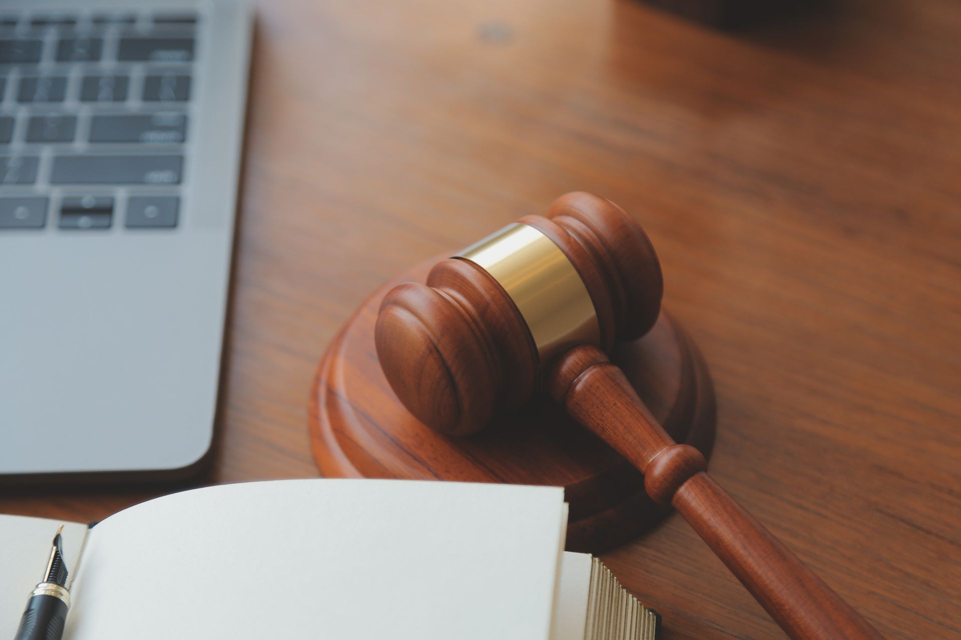 A wooden judge 's gavel is sitting on a wooden table next to a notebook and pen.