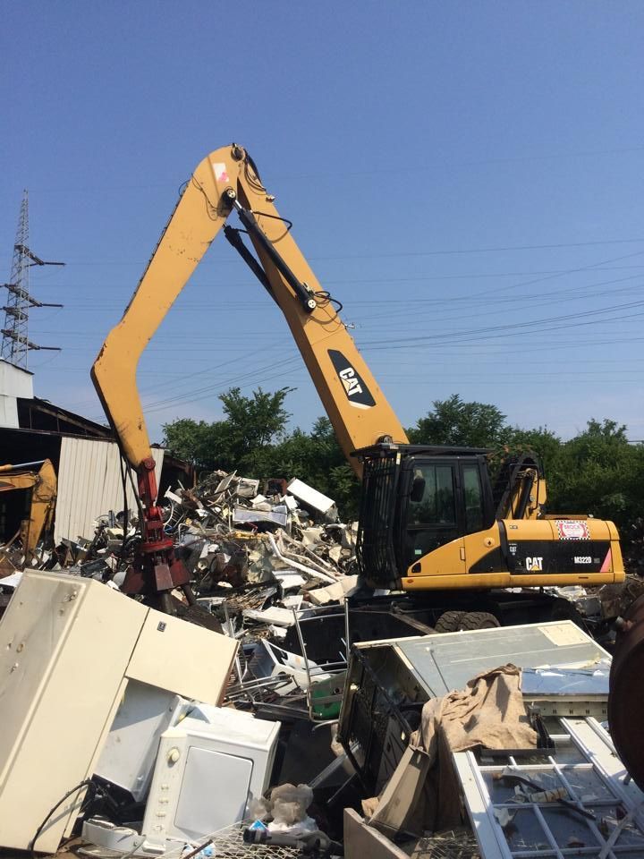 A cat excavator is moving a pile of scrap metal.