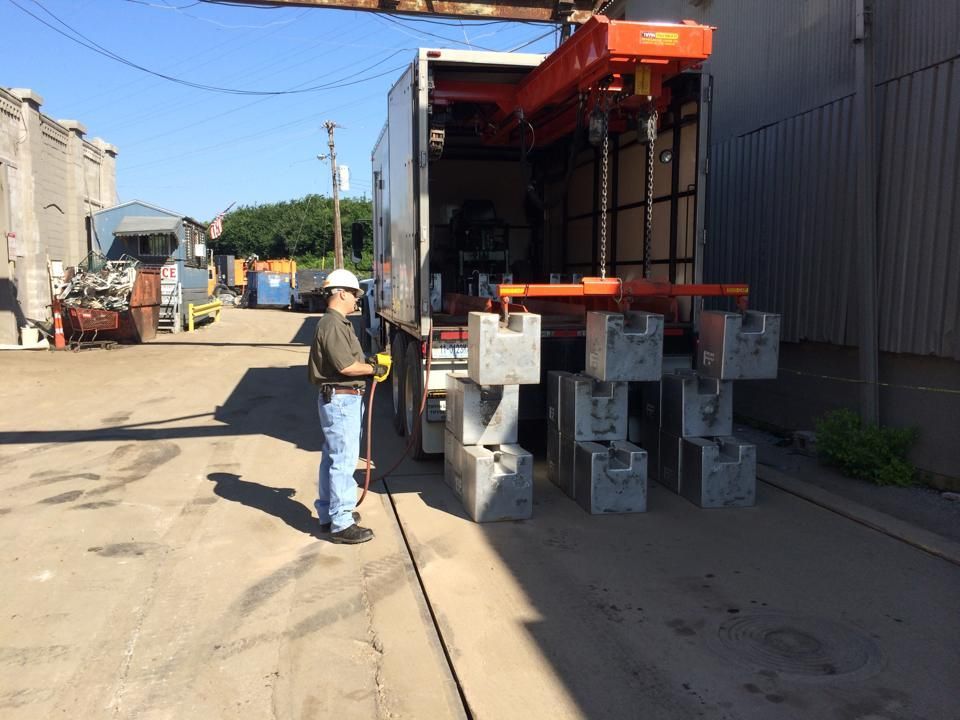 A man is standing in front of a truck with a crane attached to it.