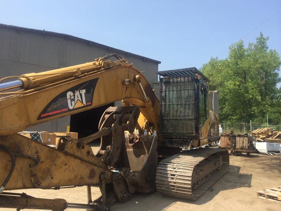 A cat excavator is parked in front of a building.