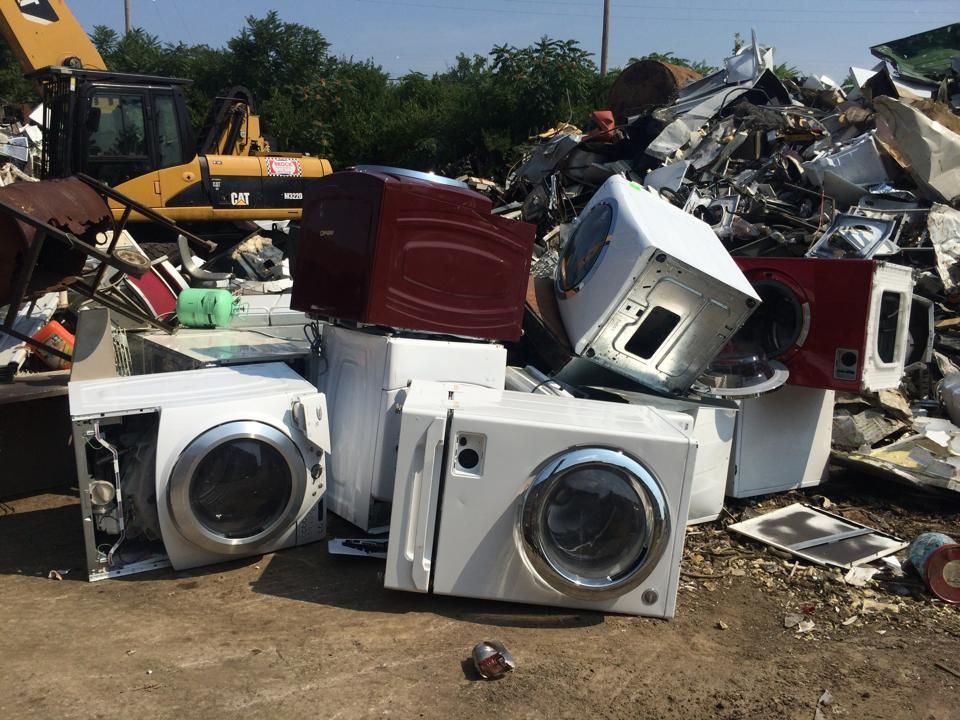 A pile of old appliances including a washer and dryer