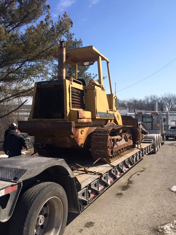 A bulldozer is sitting on the back of a semi truck.