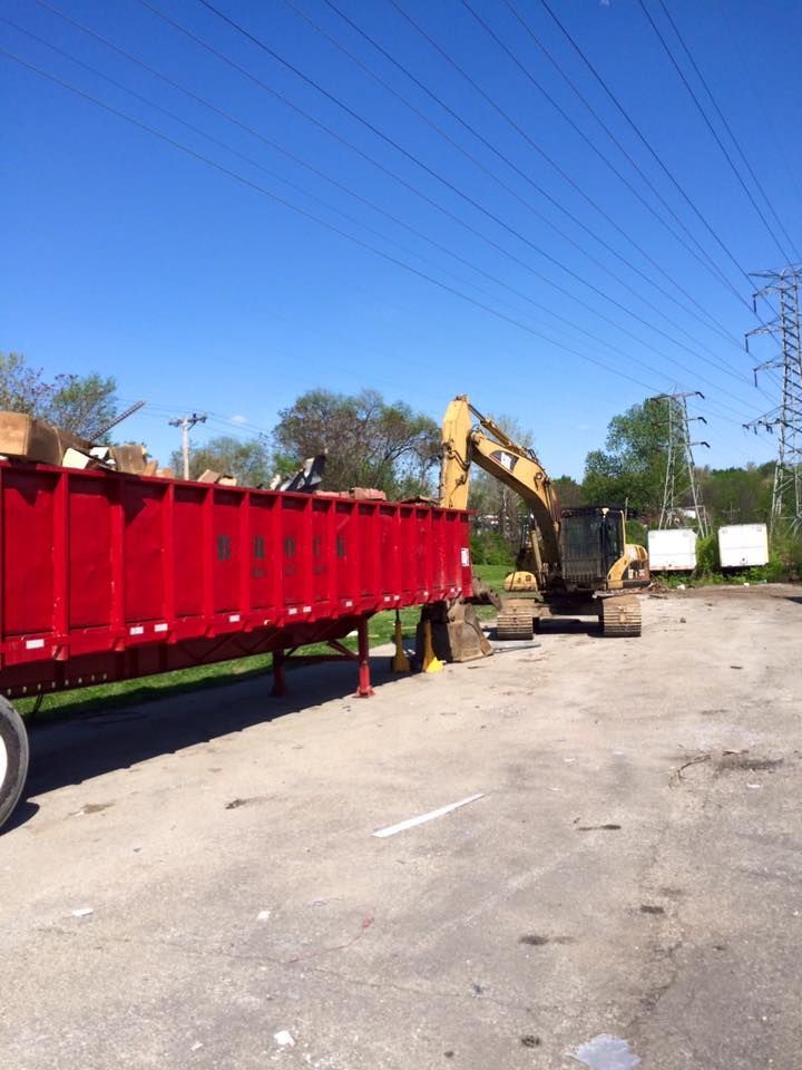A red trailer with a yellow excavator in the background