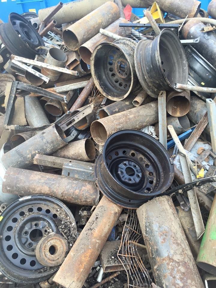 A pile of rusty metal pipes and wheels is sitting on top of each other.
