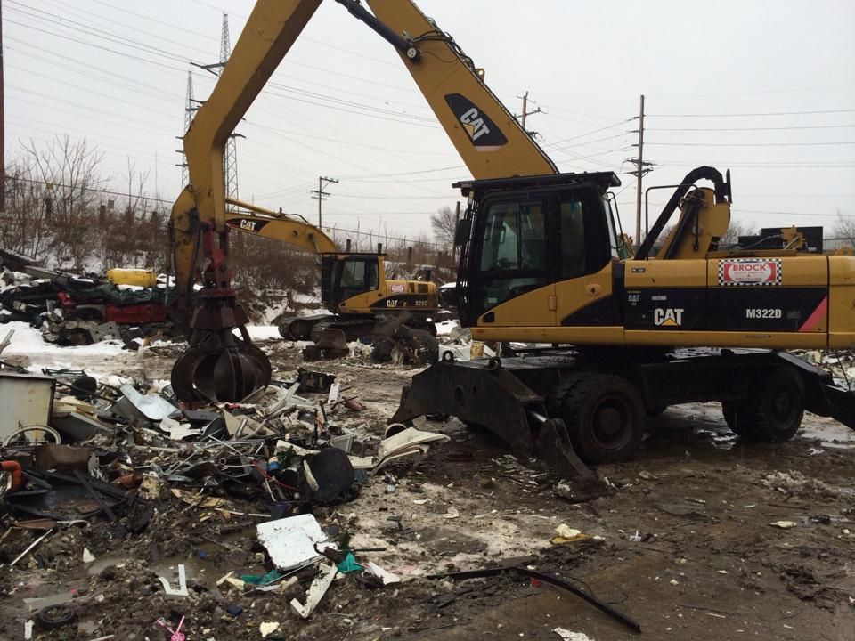 Two cat excavators are working in a scrap yard