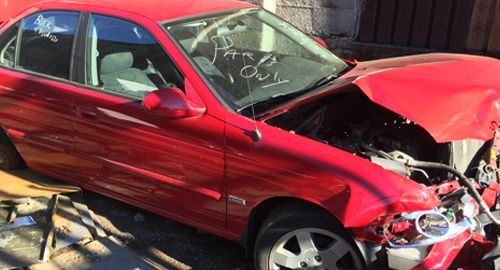 A red car with its hood up is sitting on the ground.