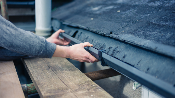 A person is installing a gutter on a roof.