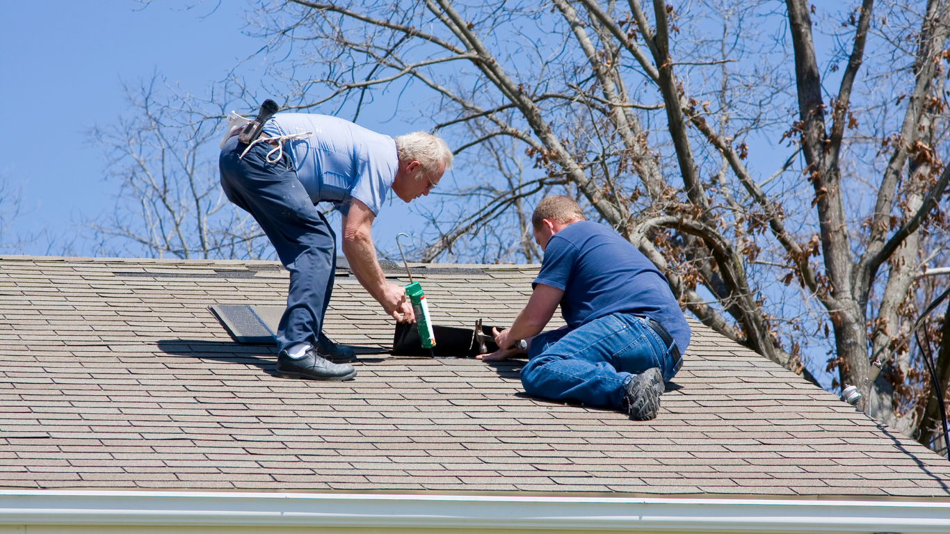 Two men are working on the roof of a house.