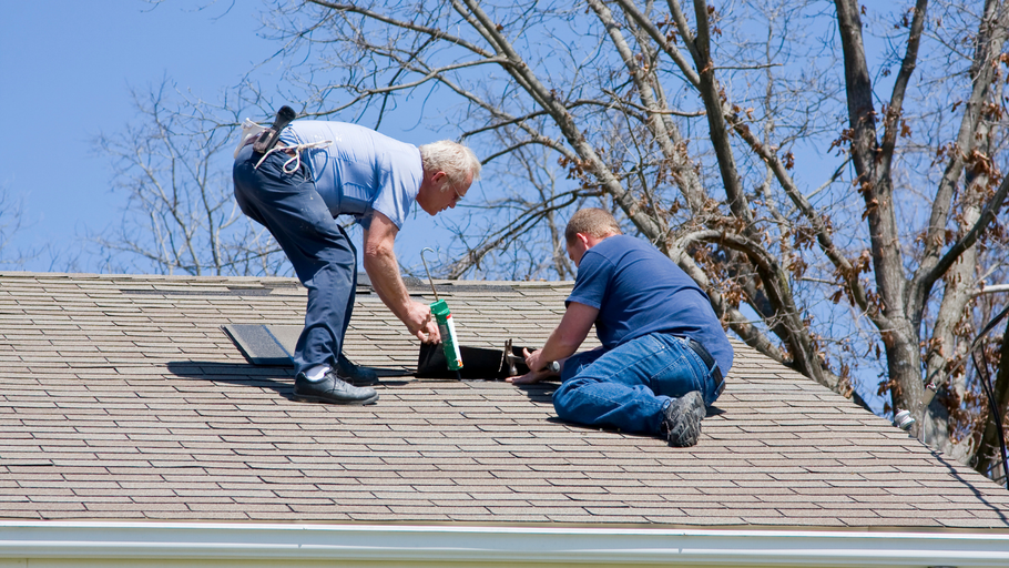 Two men are working on the roof of a house.
