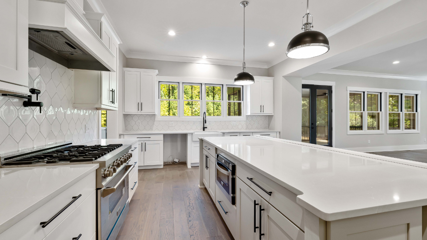 A kitchen with white cabinets , stainless steel appliances , and a large island.