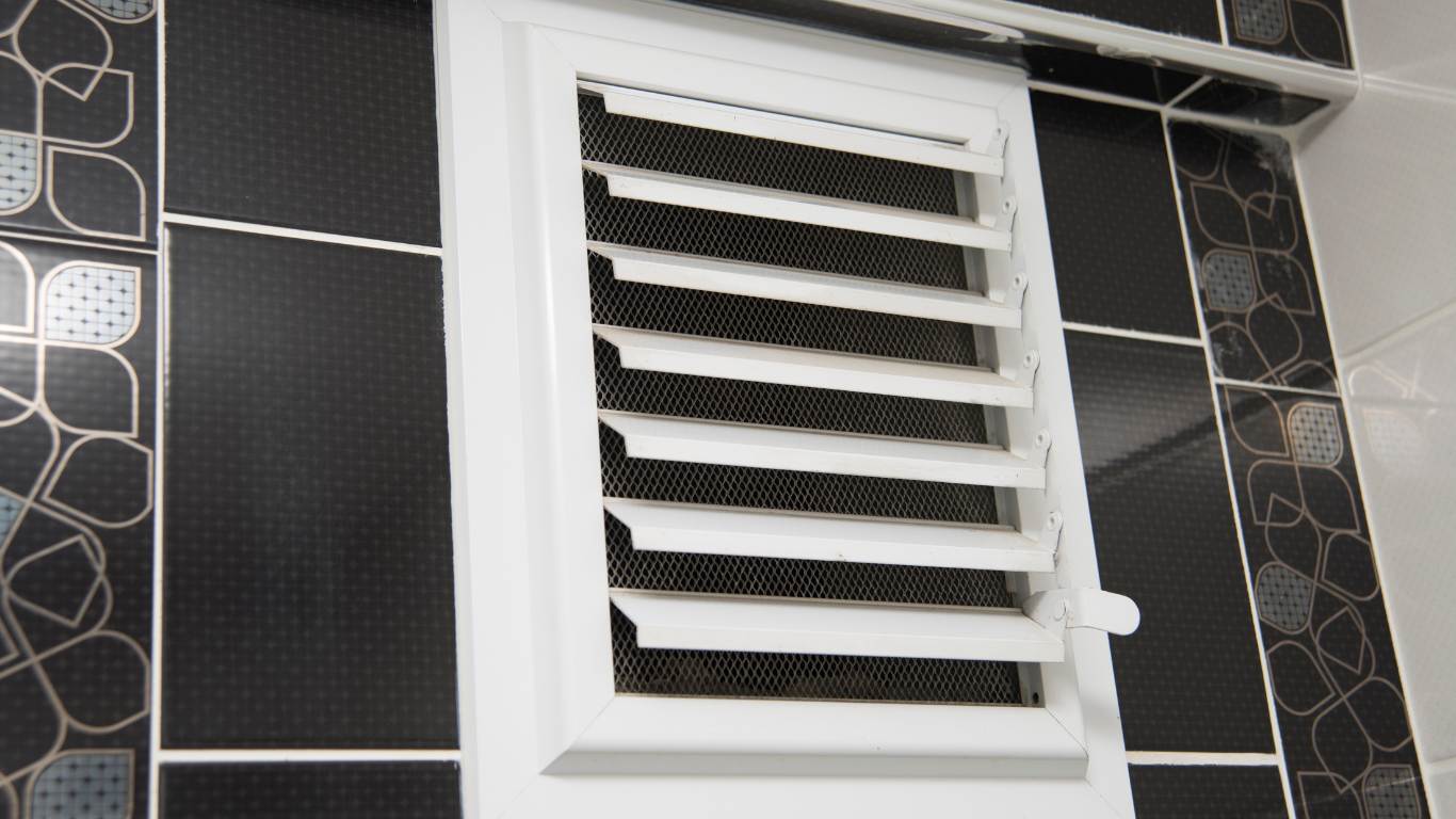 A bathroom with black tiles and a white window.