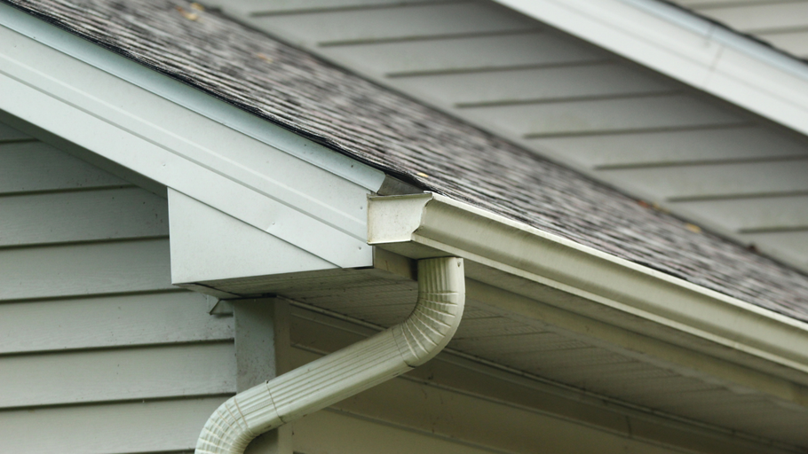 A close up of a gutter on the side of a house.