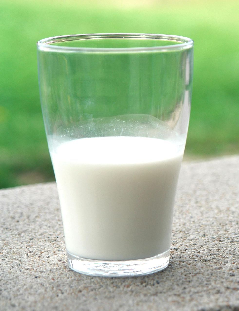 A glass of milk is sitting on a table.