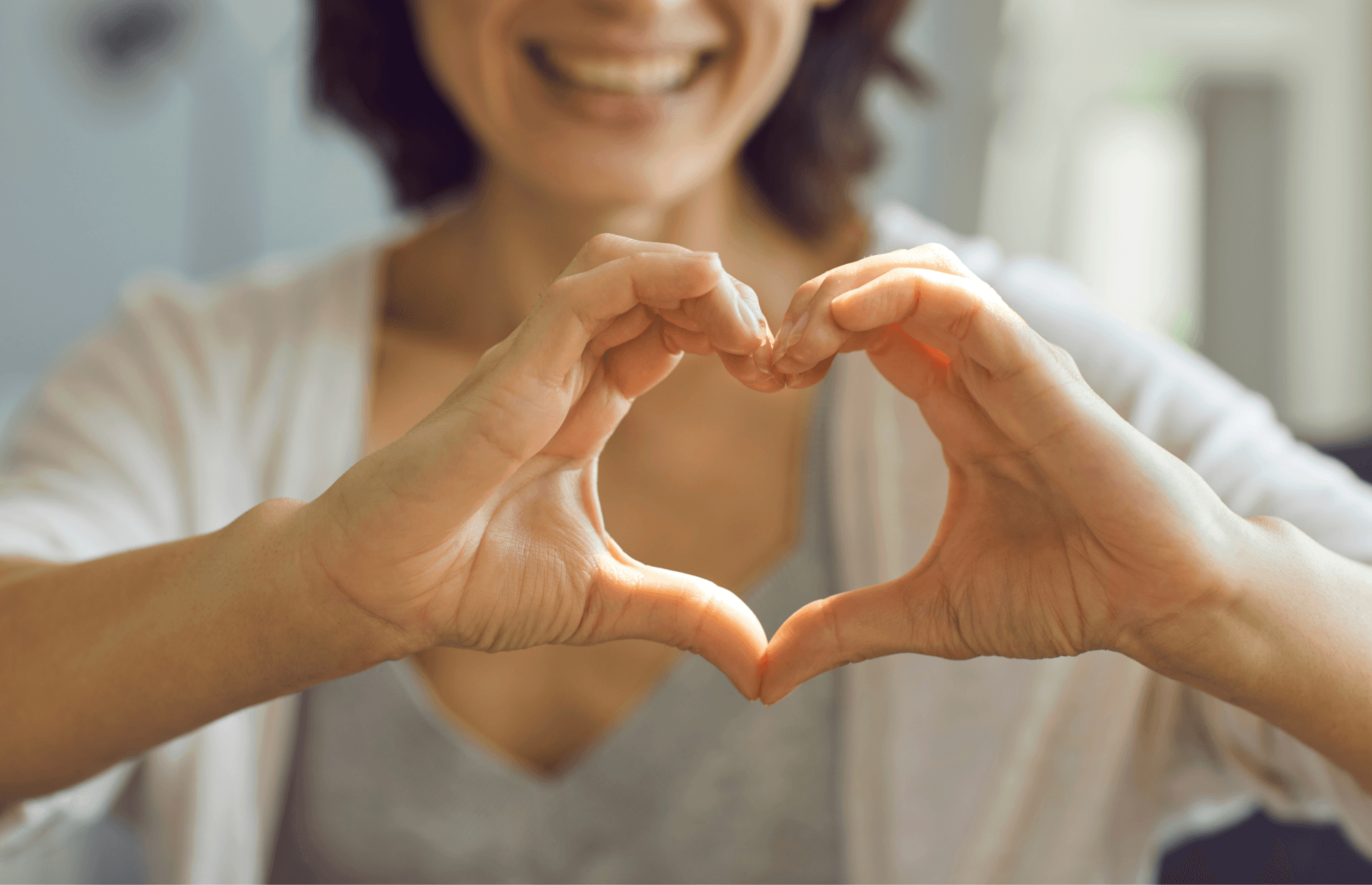 A woman is making a heart shape with her hands.