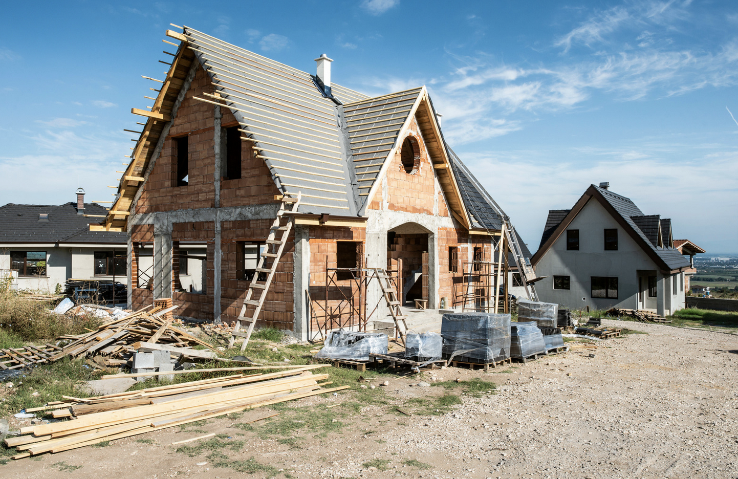 A brick house is being built in a residential area.