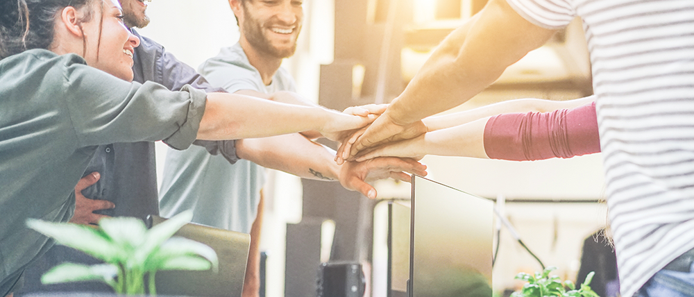 A group of people are putting their hands together in an office.