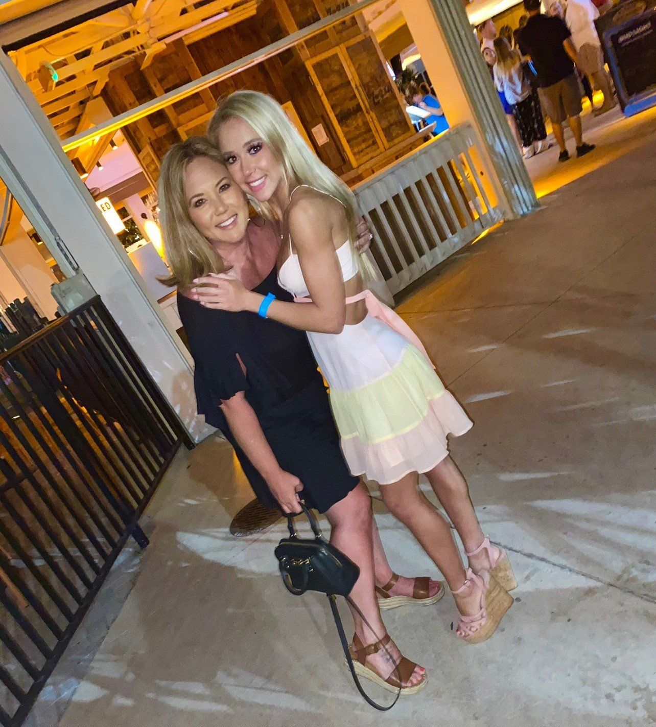 Two women are posing for a picture on a sidewalk