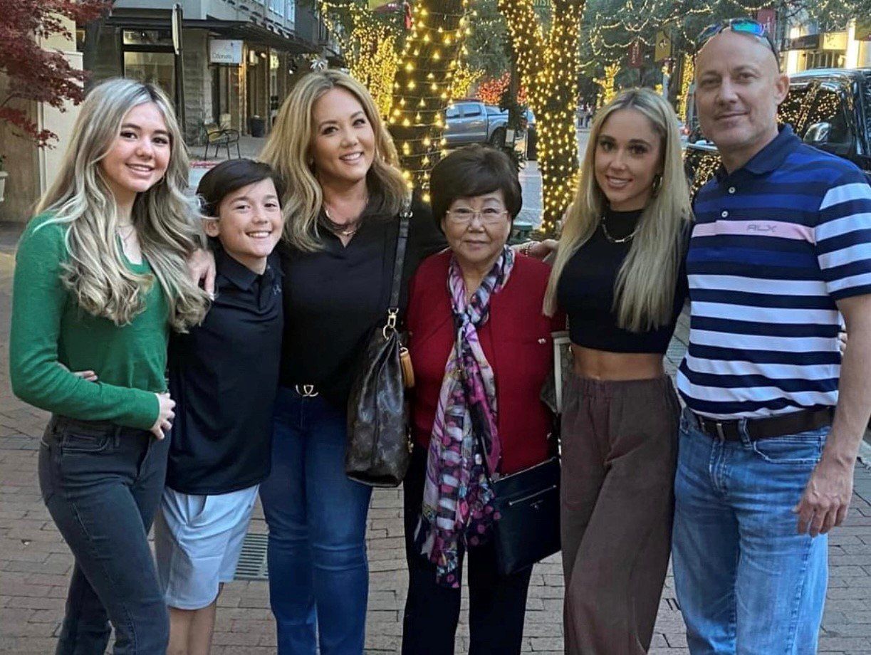 A family is posing for a picture together on a sidewalk.