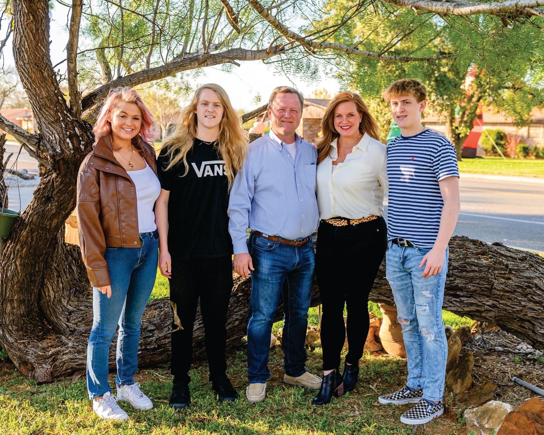 A family posing for a picture with a man wearing a vans shirt