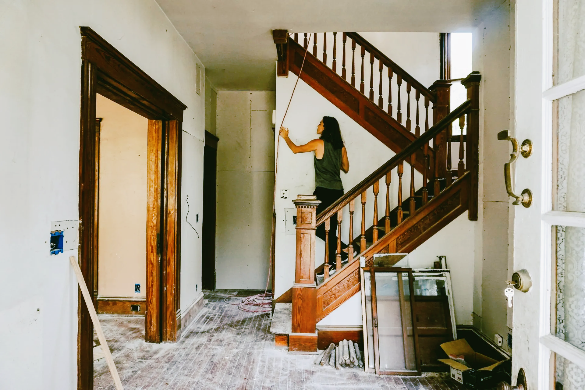 A woman is standing on a wooden staircase in a house.
