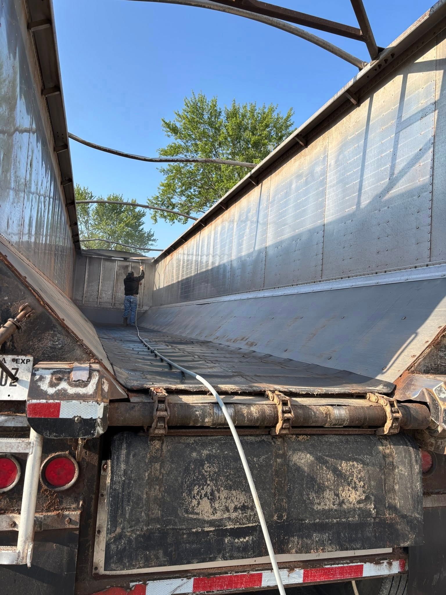 A man is standing in the back of a dump truck.