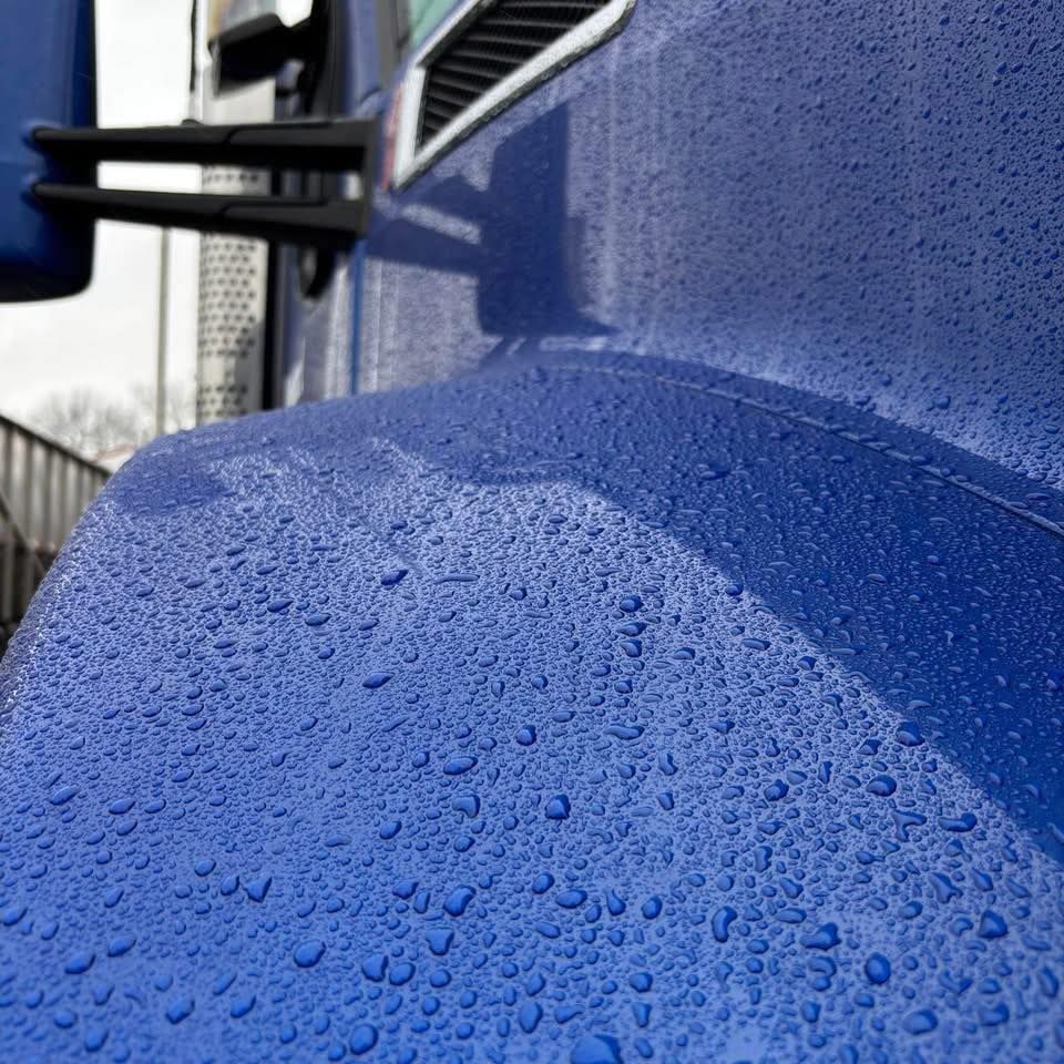 A close up of a blue truck with water drops on it