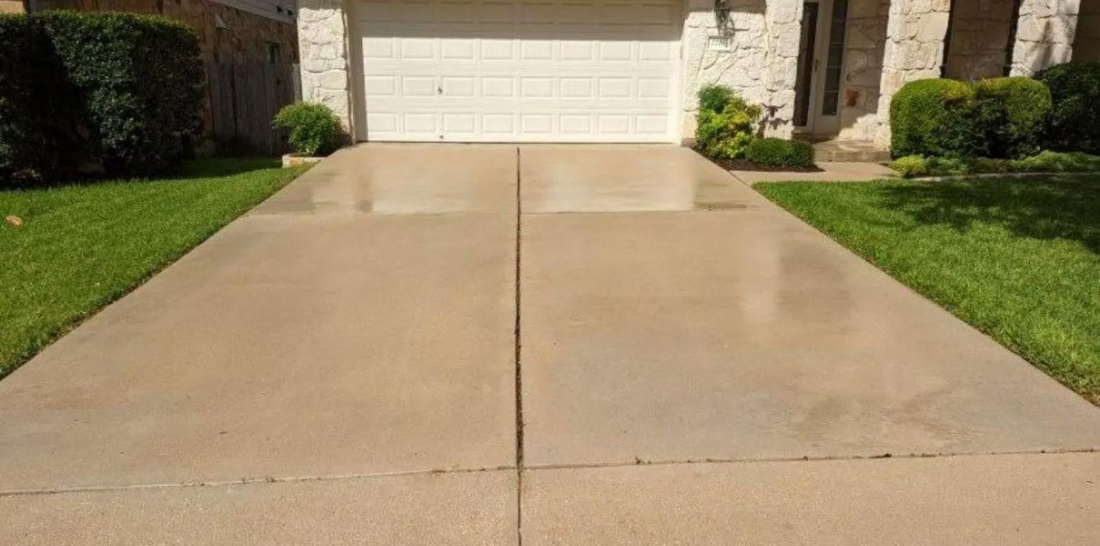 A concrete driveway leading to a house with a white garage door.