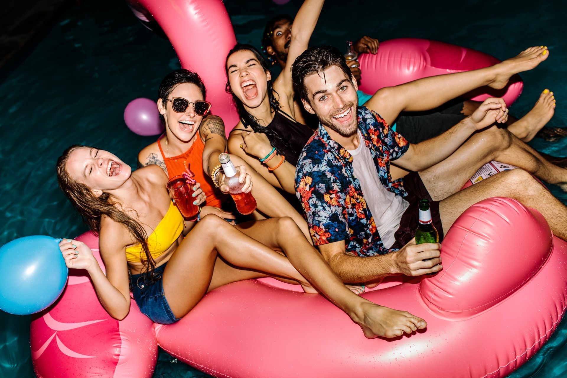 A group of people are floating on pink flamingos in a pool.