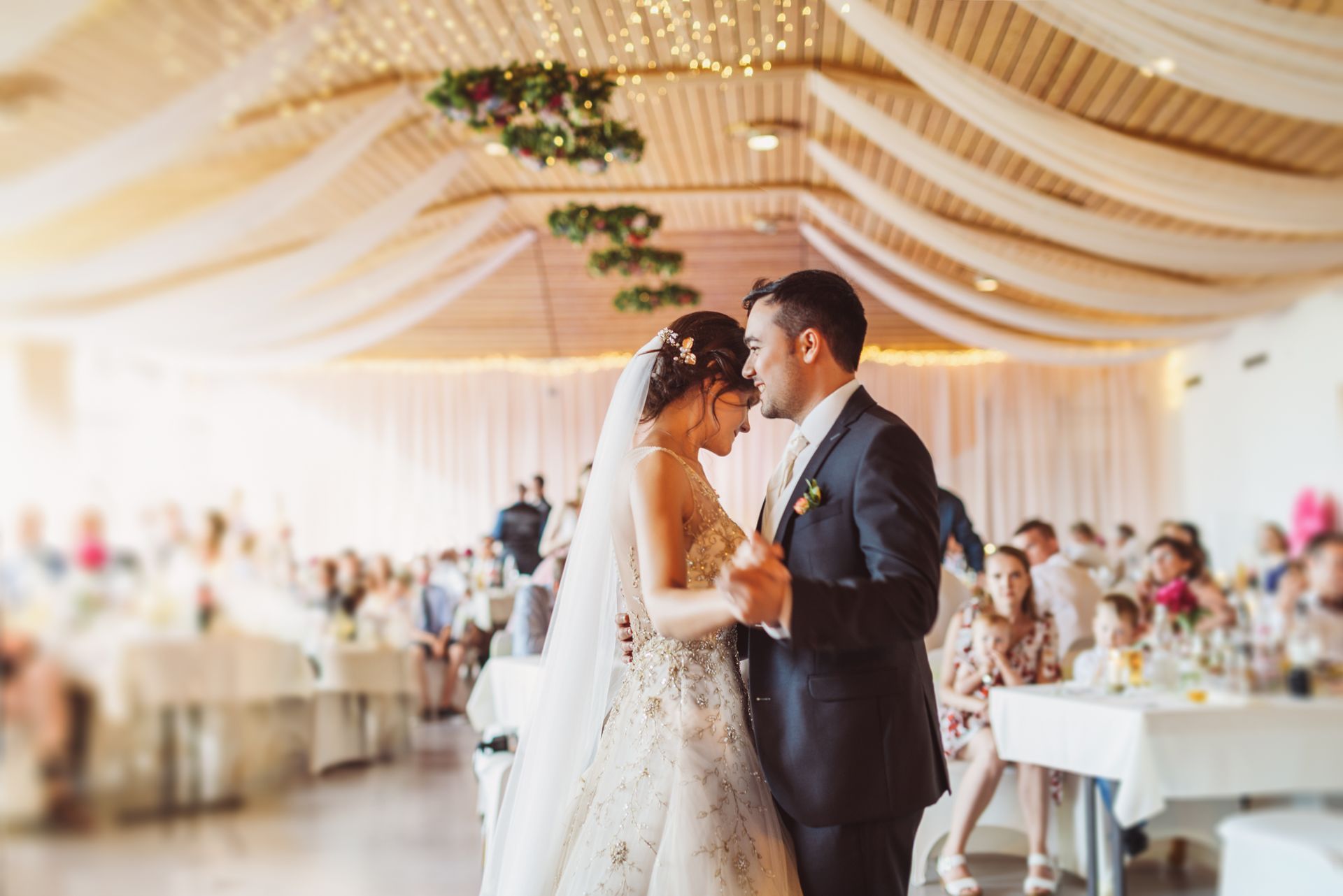 A bride and groom are dancing at their wedding reception in a large room.