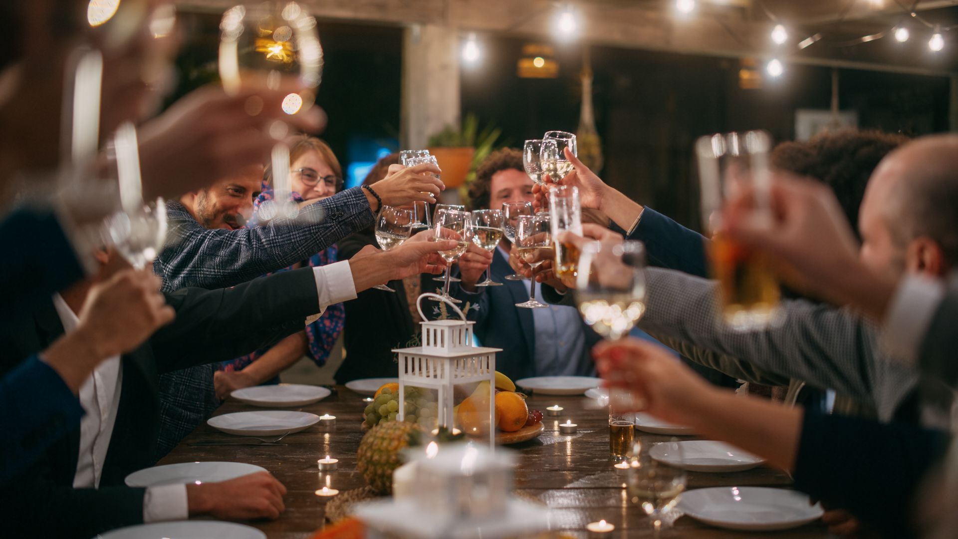 A group of people are sitting at a table toasting with wine glasses.