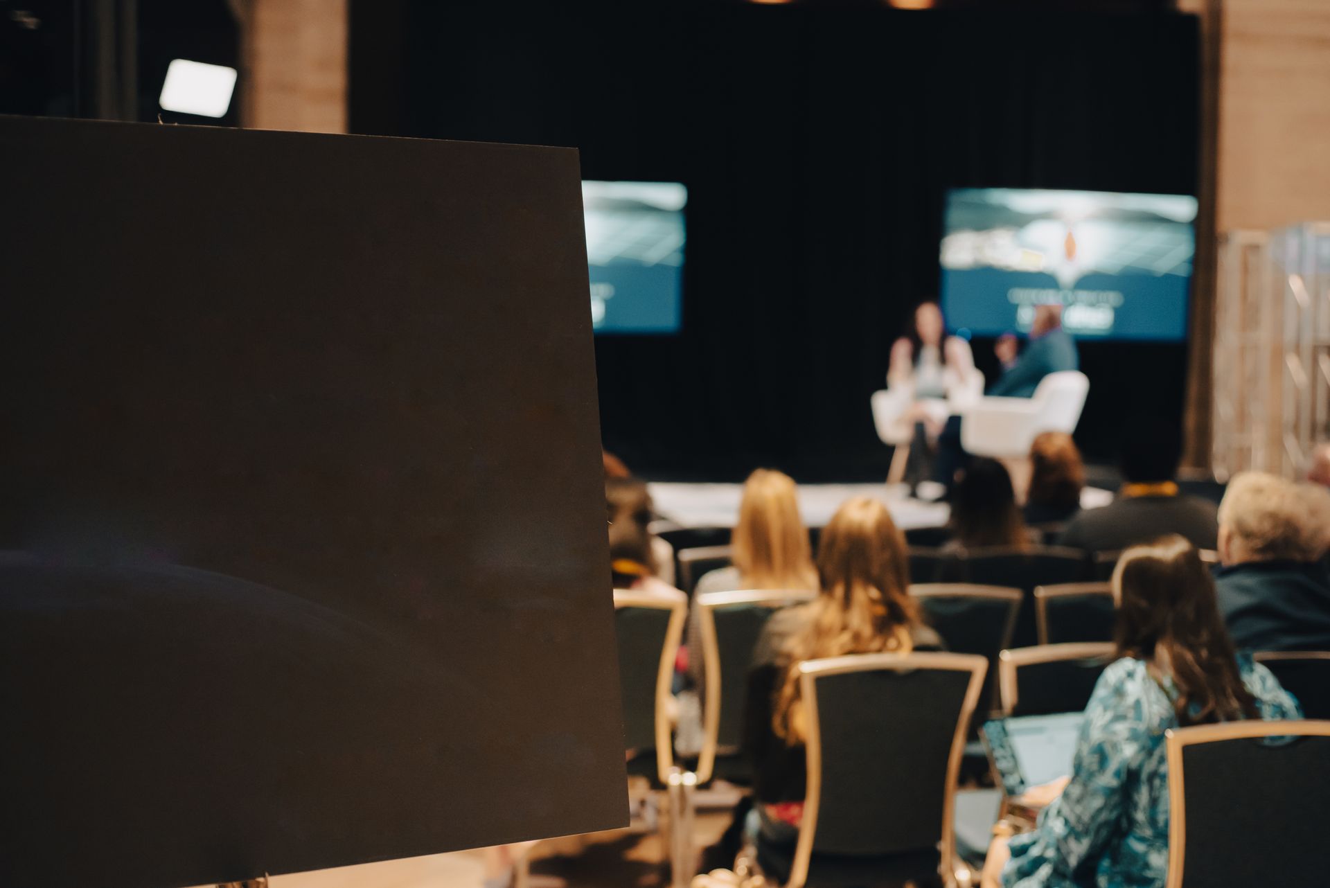 A group of people are sitting in a conference room watching a presentation.