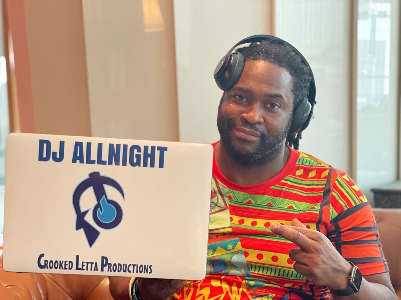 A man wearing headphones is holding a sign that says dj allnight