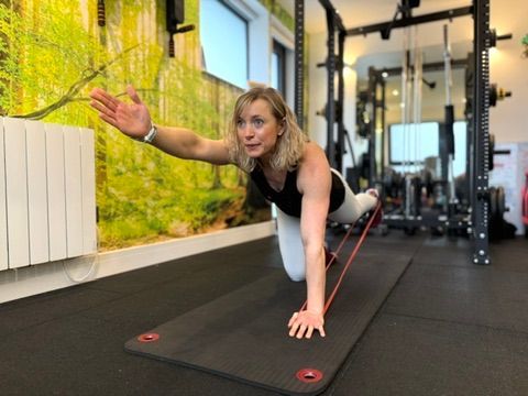 A woman is doing exercises on a mat in a gym.