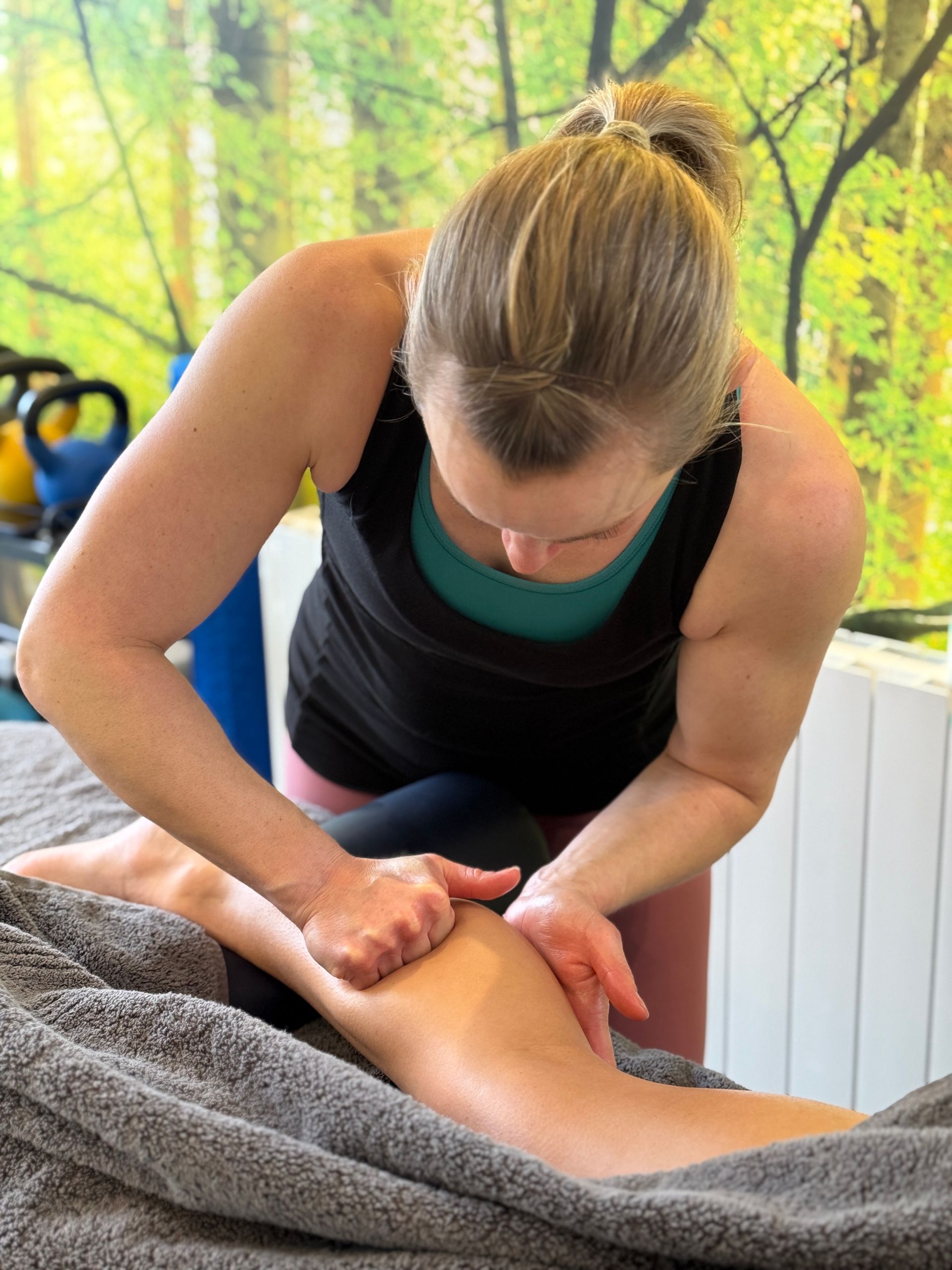A woman is giving a massage to a person 's leg.