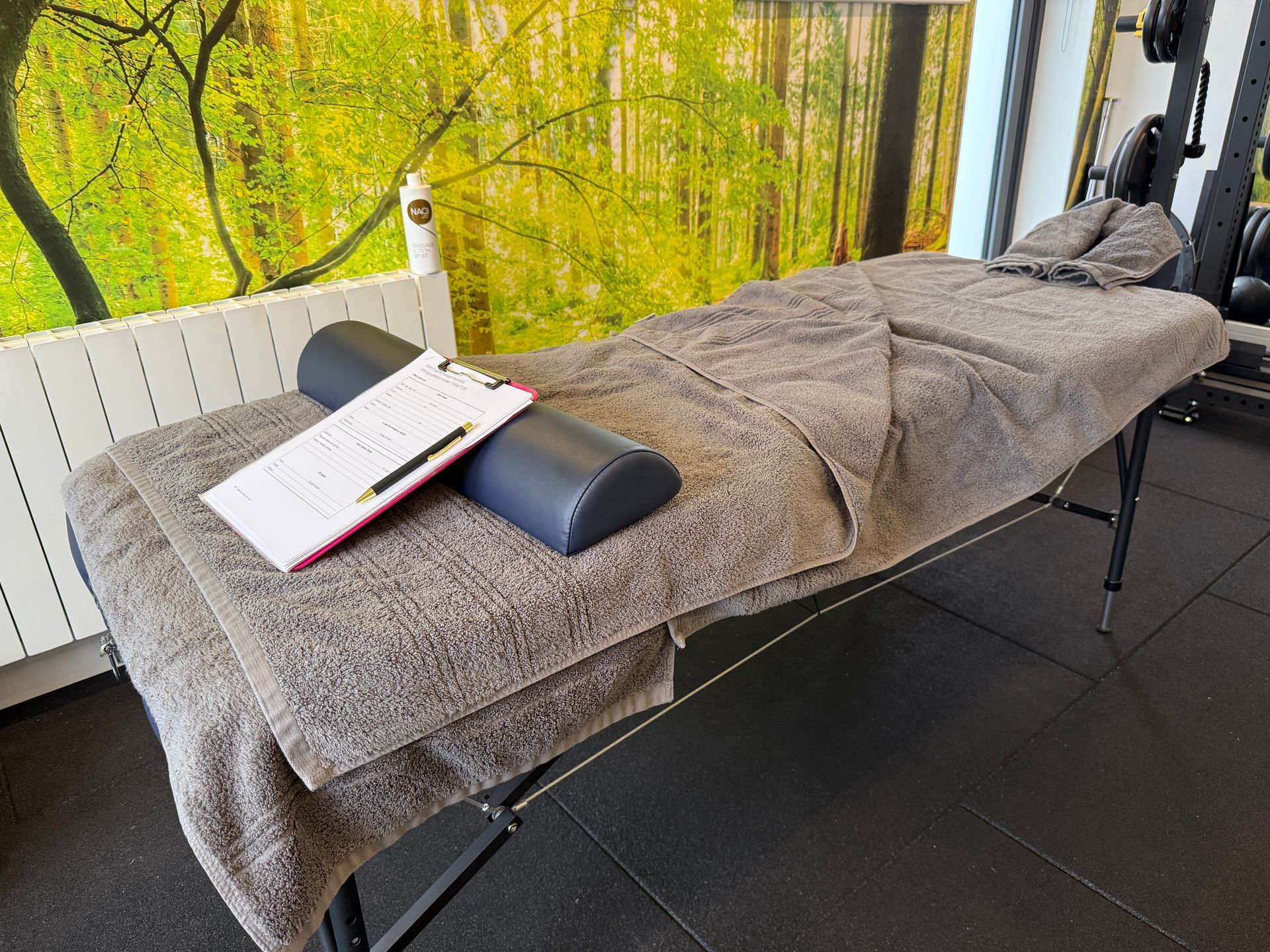 A massage table with a towel and a clipboard on it in a gym.