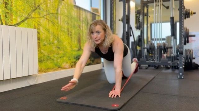 A woman is doing exercises on a yoga mat in a gym.