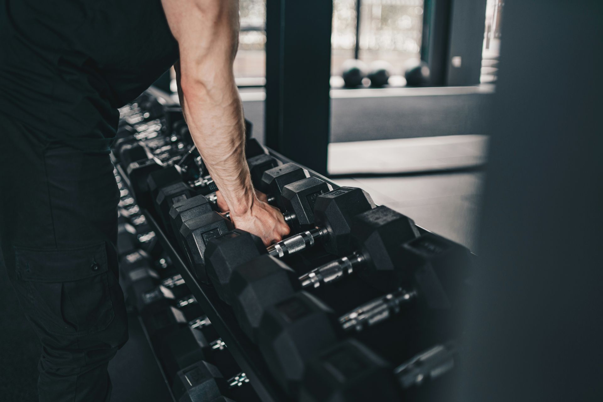A man is holding a dumbbell in his hand in a gym.