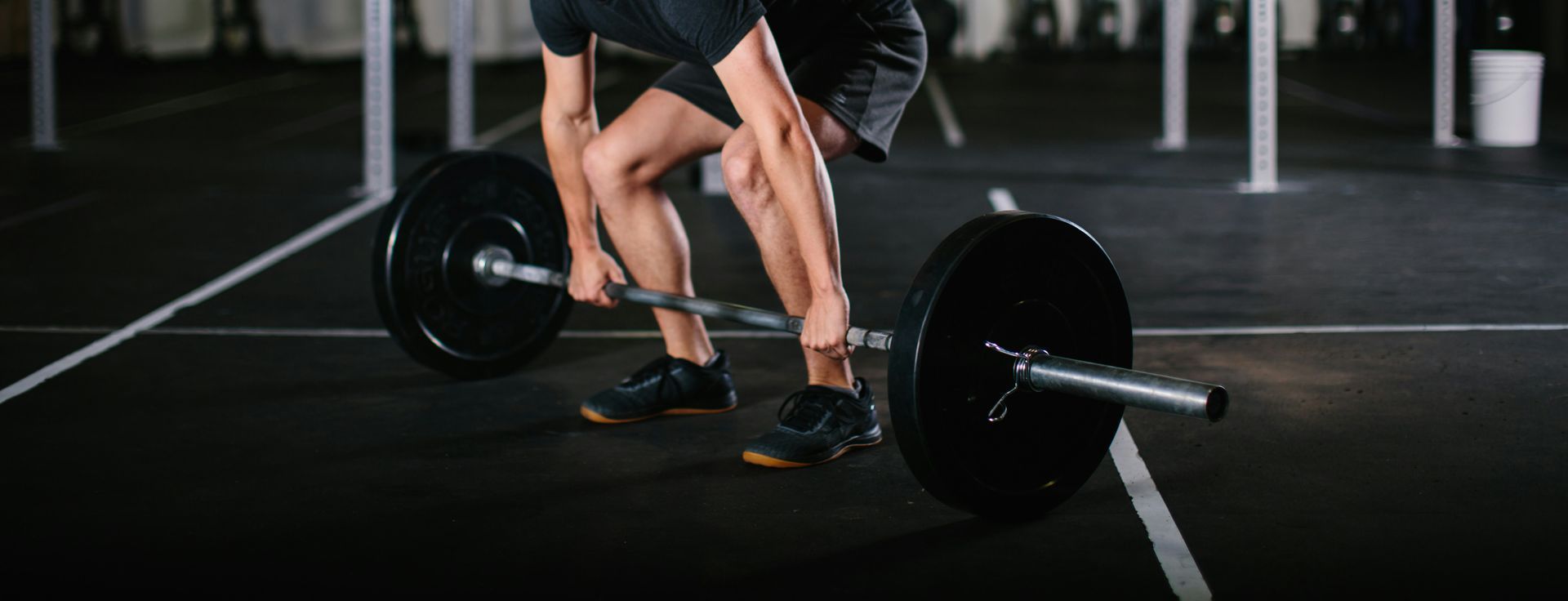 A man is lifting a barbell in a gym.