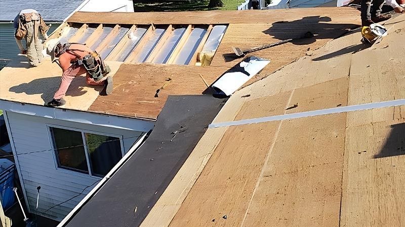 A group of men are working on the roof of a house.