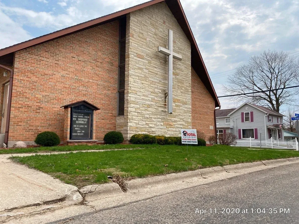 A large brick church with a cross on the side of it.