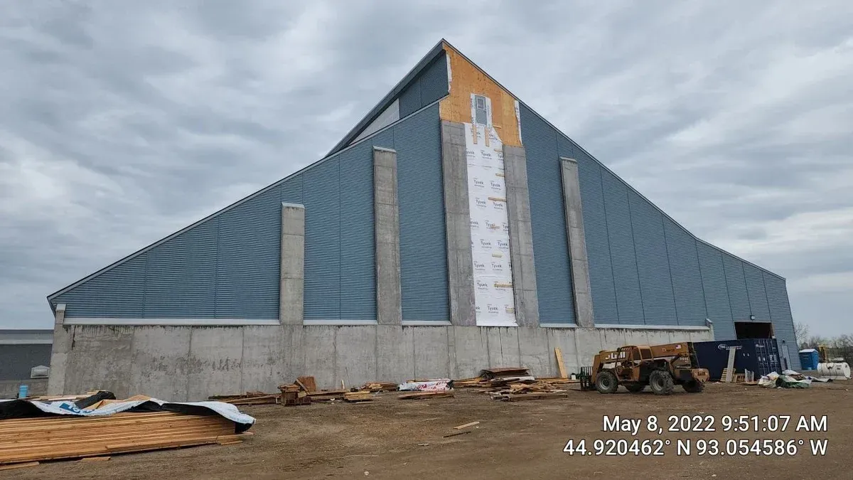 A large building with a pyramid shaped roof is under construction.