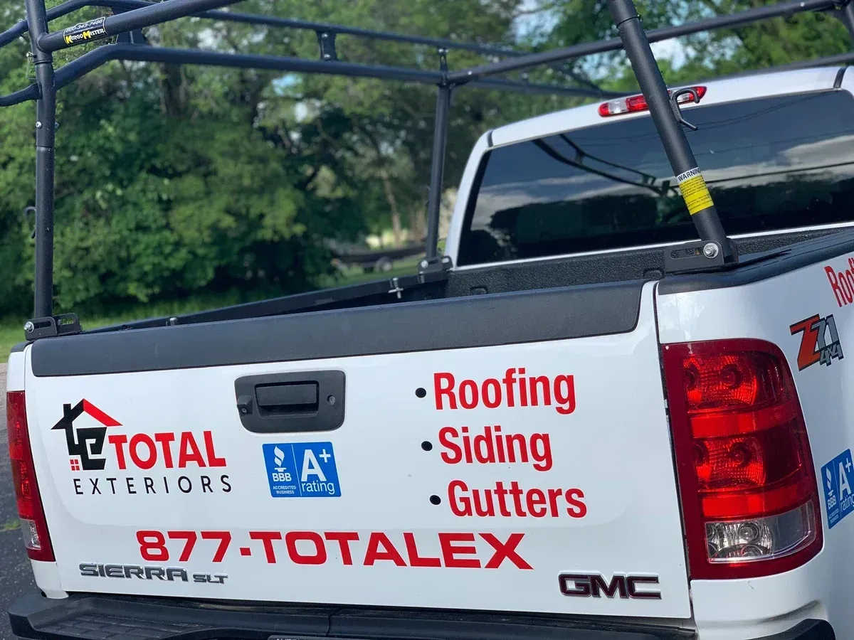 A white truck with a roofing siding and gutters sticker on the back
