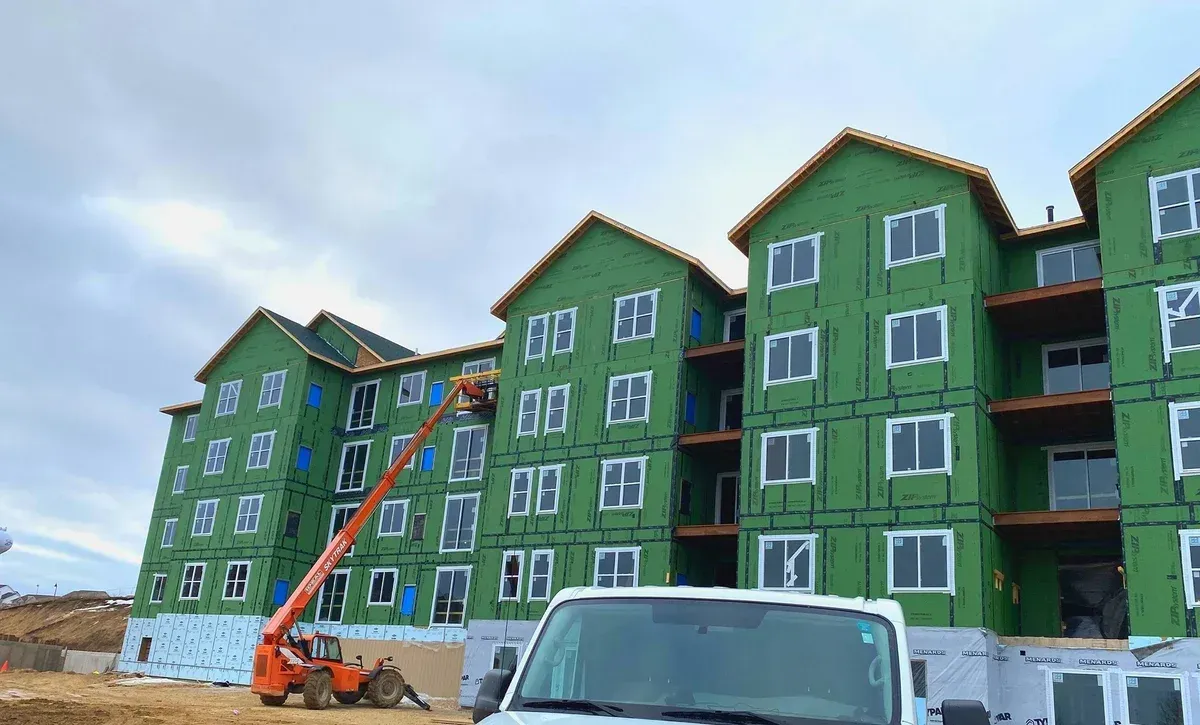 A white van is parked in front of a building under construction.