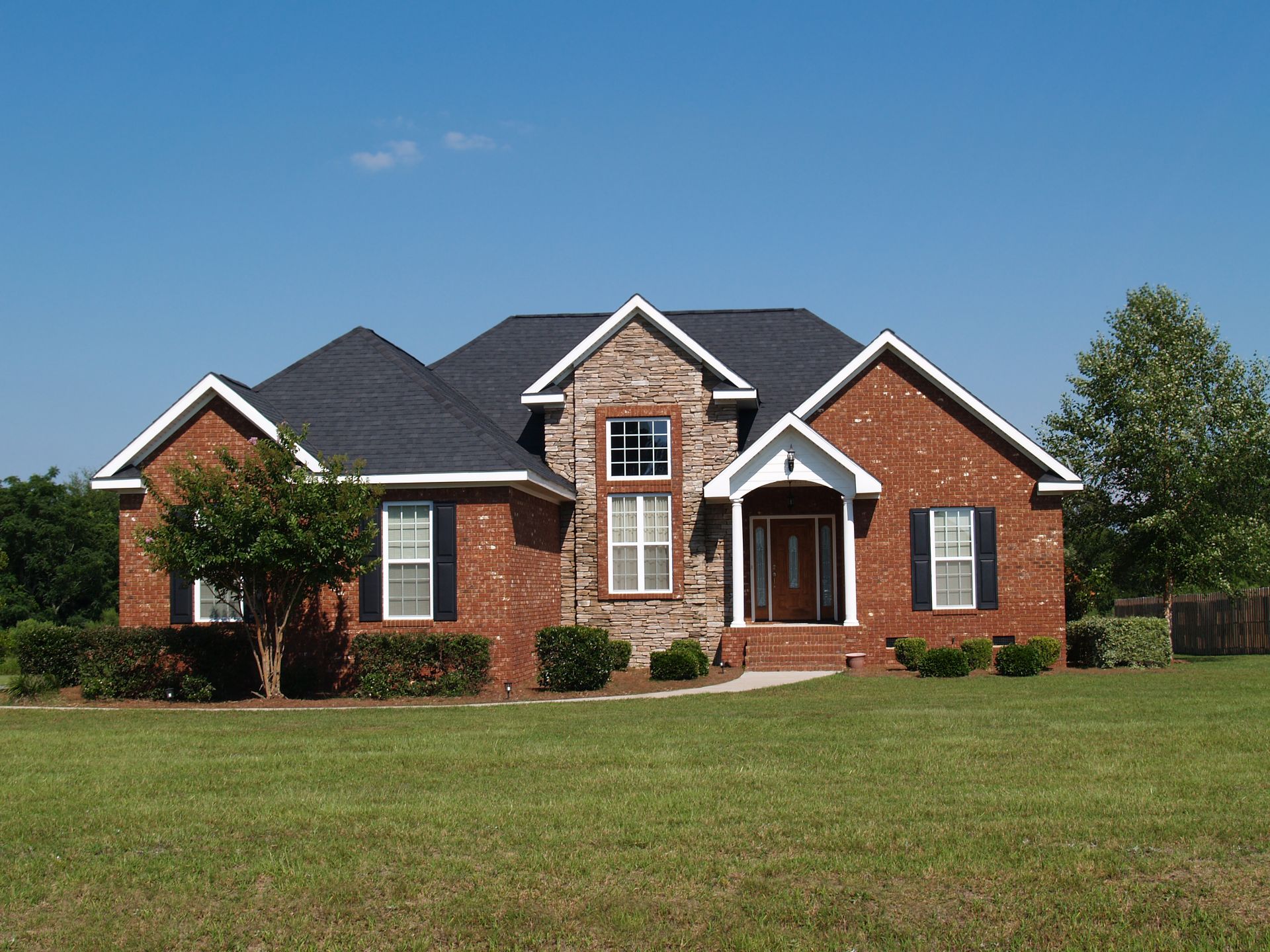 A large brick house with a slate roof and black shutters